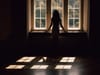 Woman standing in dark window.